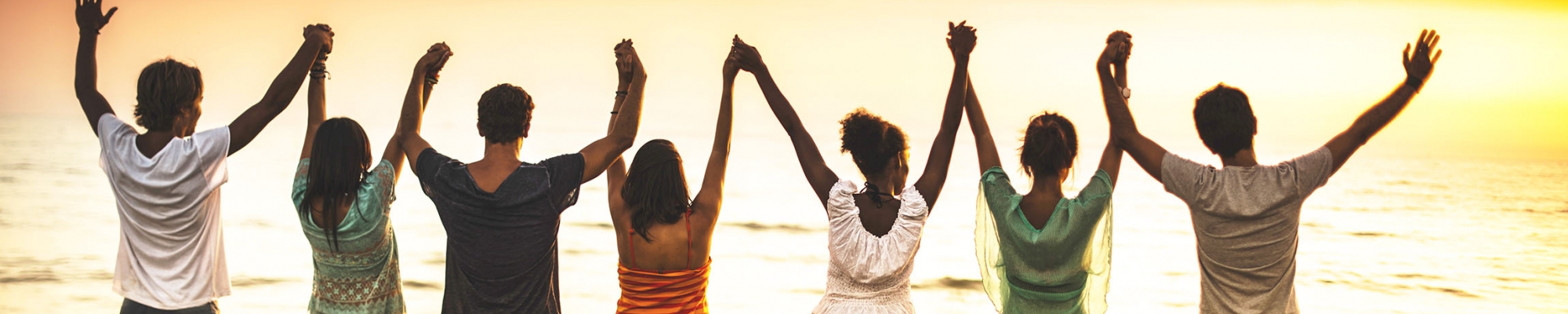 People standing on a beach with hands raised up