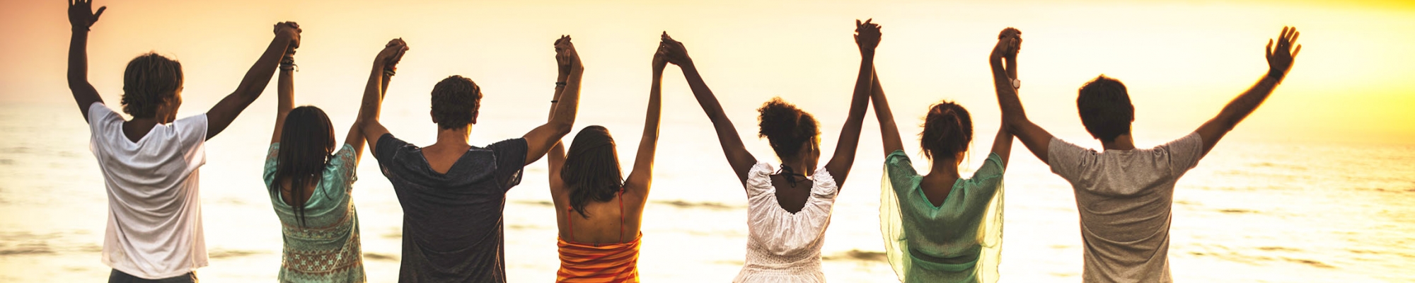 Group of people standing on a beach with hands raised